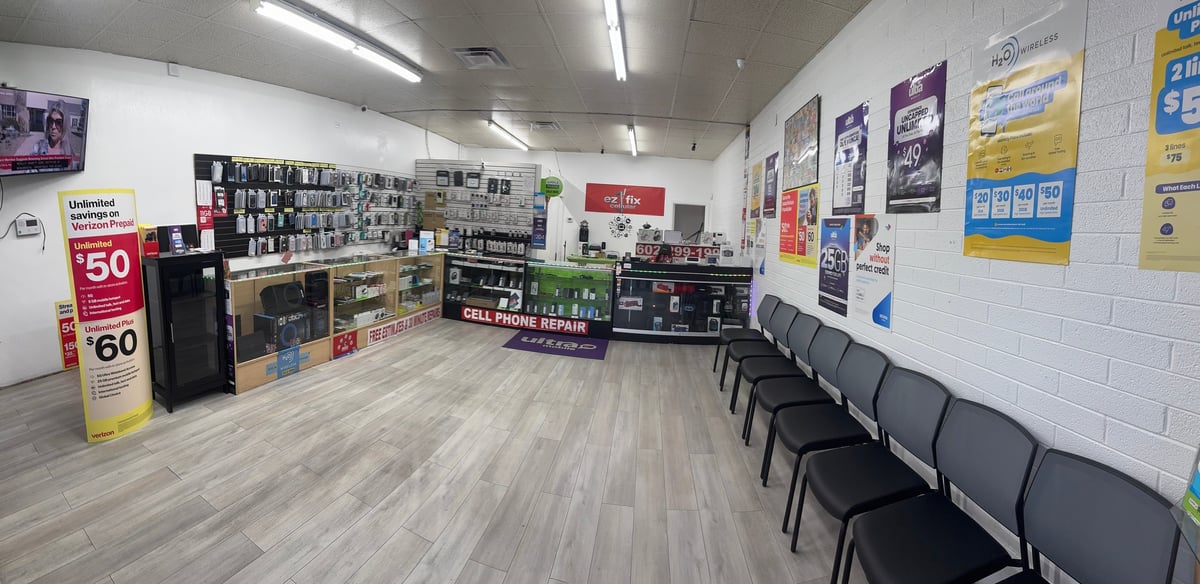 Interior of EZ FiX Cellular store with product displays, discount signs, posters on walls, and seating chairs